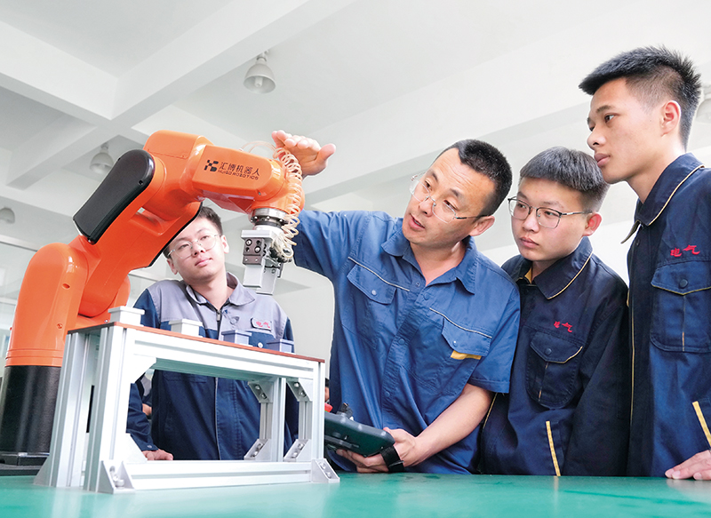 河北省秦皇岛工业职业技术学院的老师（右三）给电气工程专业学生讲解机器人的工作原理 ... ...